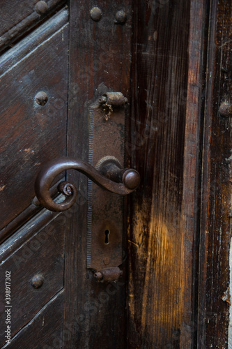 An old forged iron handle in a wooden door in the side gate leading to the garden in the courtyard of the convent