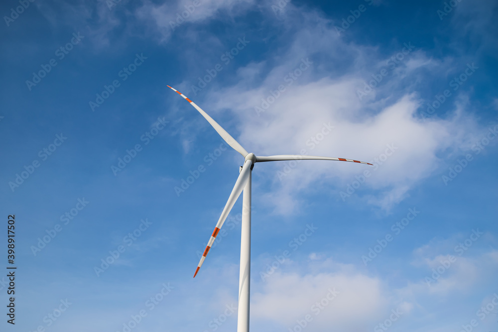 Close up of the rotor of a giant wind turbine against a blue sky with white clouds Close up of the rotor of a giant wind turbine against a blue sky with white clouds