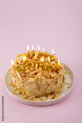 Close up of Happy birthday cake with burning candles on pink surface