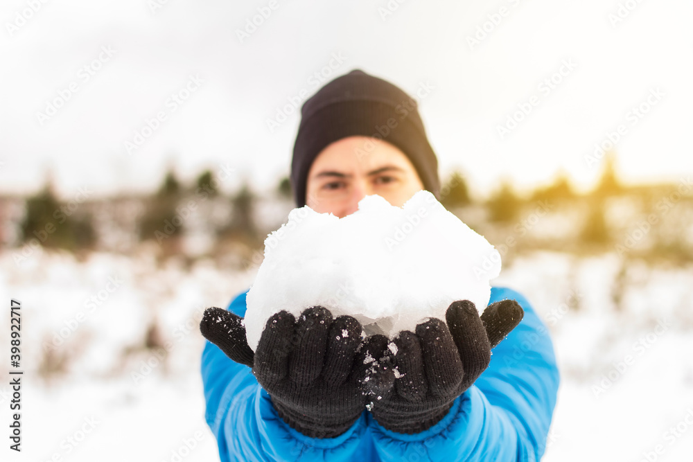 Hands of a man in a blue jacket holding a snowball on a snowy mountain in winter. Stock Photography.