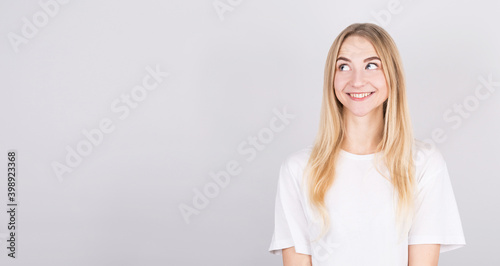 Photo of amazing smiling blonde girl looking up empty space isolated on grey background with copyspace.