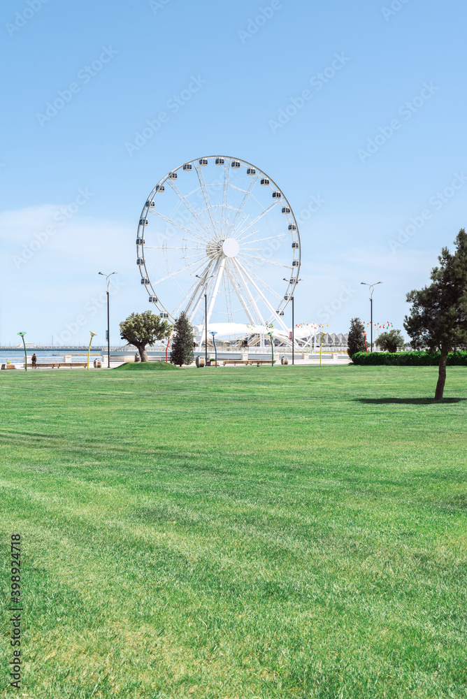 white Ferris wheel with green grass lawn in Baku, Azerbaijan white Ferris wheel with green grass lawn in Baku, Azerbaijan