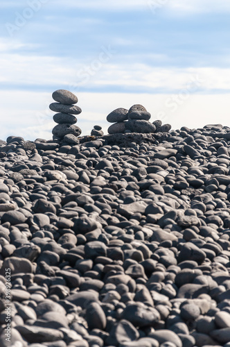 Cairns of rocks on a beach made only by black lava cobble rocks on the shore of Iceland