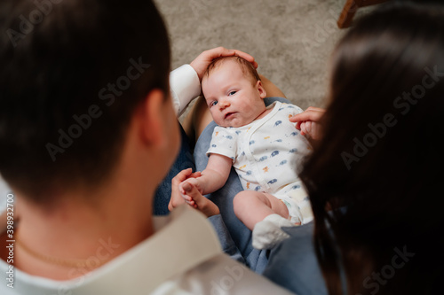 top view. shooting over shoulder. newborn baby is lying on lap of his parents