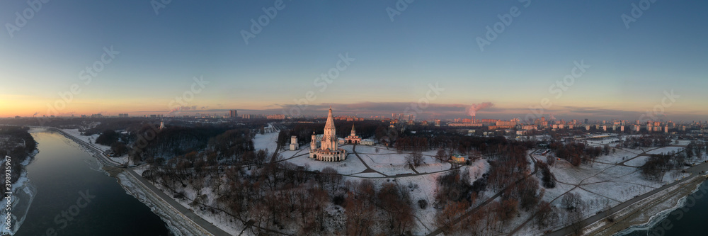 Obraz premium panoramic view of the park in the city on the river bank with old buildings at sunrise in winter filmed from a drone