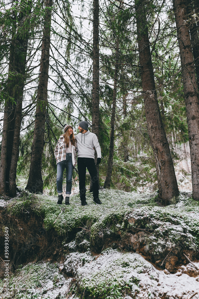Happy couple among giant fir trees with first snow