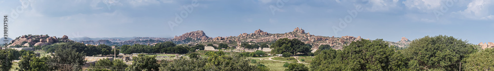 Hampi, Karnataka, India - November 4, 2013: Royal Enclosure. Panorama shot of the scenery around and above with the Mohammadan Watch Tower about in center. Rocky hills under blue sky. Green vegetation