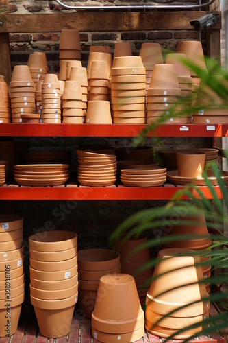 Stacks of terra cotta pottery on metal shelves at plant nursery © Simone