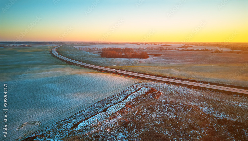 Winter green Agricultural field winter crops under snow panorama. Highway December sunset Aerial scene.