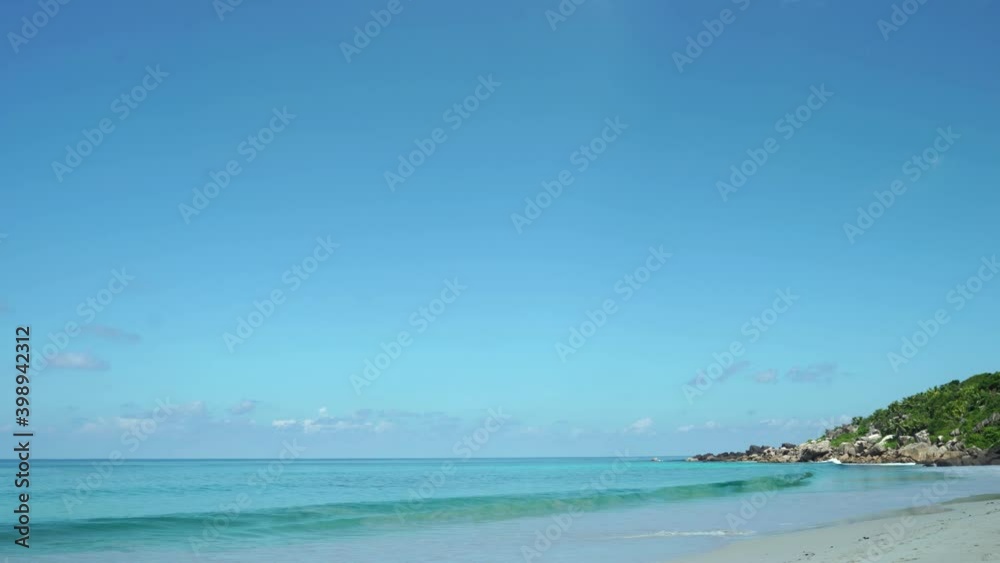 Exotic beach by the ocean with rolling waves on the sandy shore and blue sky. Exotic beach by the ocean with rolling waves on the sandy shore and blue sky.