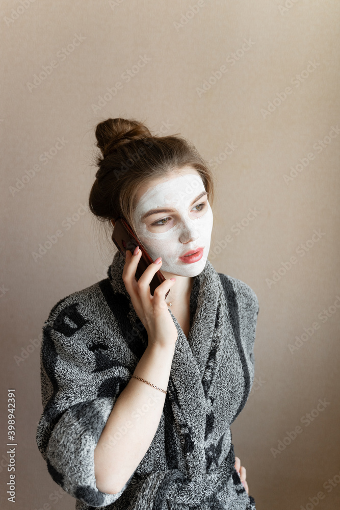 woman talking on the phone with a clay mask on her face woman talking on the phone with a clay mask on her face
