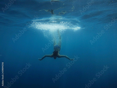 Photography girl dives into the blue water