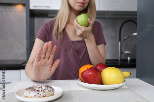 Woman refuses to eat unhealthy sweets and choose fruits for dessert. Healthy eating and active lifestyle concept