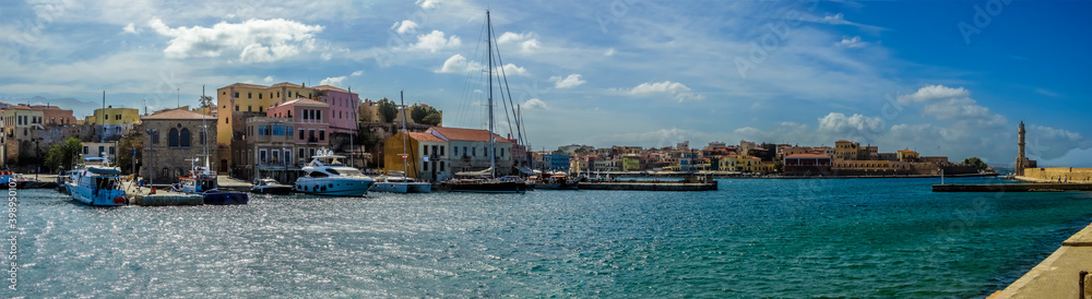 Obraz premium A panorama view from the inner harbour of Chania, Crete looking out to the harbour entrance on a bright sunny day