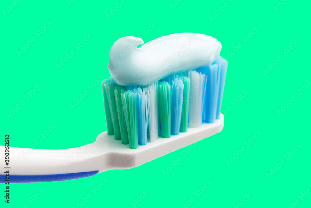 Toothbrush head with toothpaste on mint green background, close-up view, macro Toothbrush head with toothpaste on mint green background, close-up view, macro
