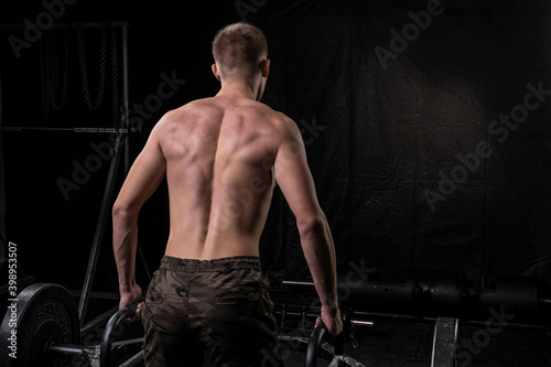 photo of the back of a young alet who lifts the barbell