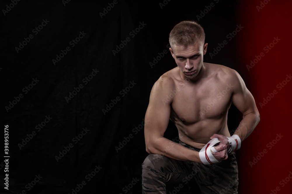 a young man of athletic build with a naked torso wraps elastic bandages on his wrists a young man of athletic build with a naked torso wraps elastic bandages on his wrists