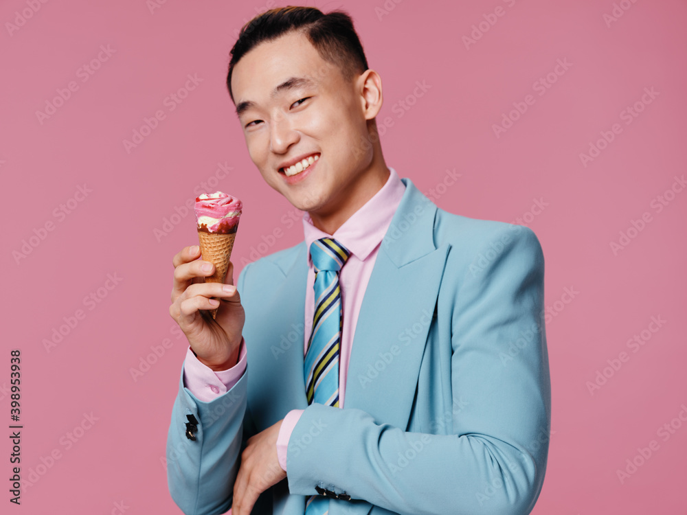 Smiling man of Asian appearance wearing suit with ice cream hands pink background Smiling man of Asian appearance wearing suit with ice cream hands pink background