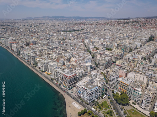 Aerial drone view of iconic historic landmark - old byzantine White Tower of Thessaloniki or Salonica with traditional tourist boats travelling Thermaikos gulf, North Greece