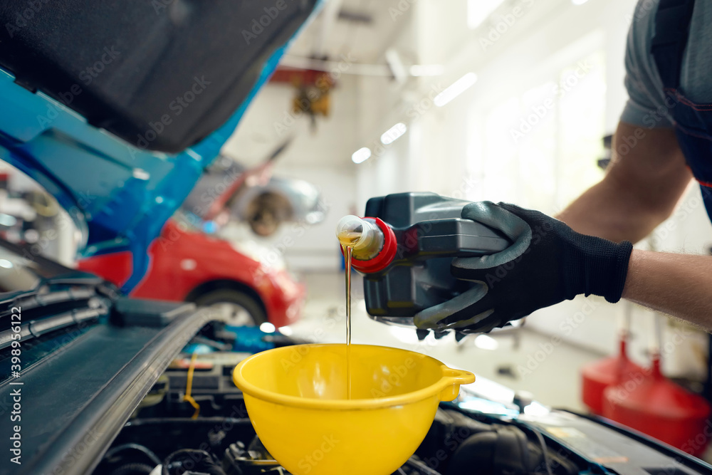 Pouring oil into engine at car service station Pouring oil into engine at car service station