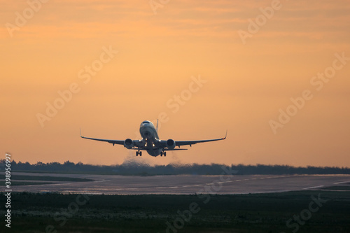 Commercial twin engine airplane taking off at sunset
