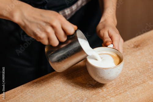 Barista's hands whip milk foam to make cappuccino. High quality photo