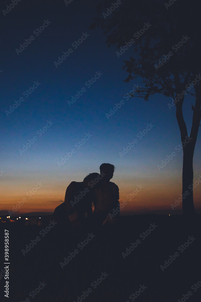 Couple sitting on a hill with sunset in the background