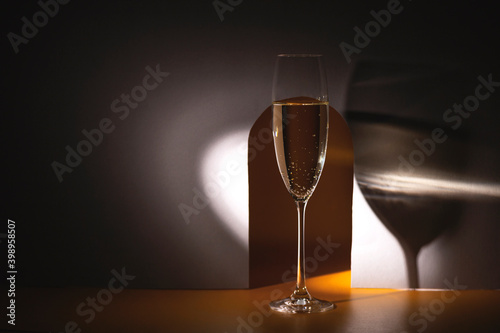 Glass of champagne in a round beam of light on a gray background with an arch.. Holiday and New Year concept. Copy space
