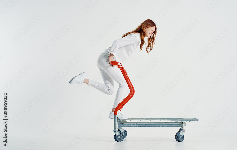 woman courier with a cargo trolley on a light background in full growth