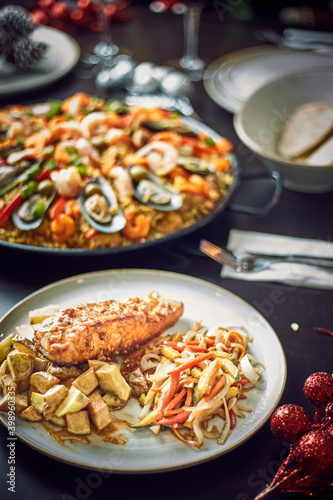 Spanish dinner table with assortment of dishes. paella, octopus, whole fish, sangría and wine. Dressed for christmas