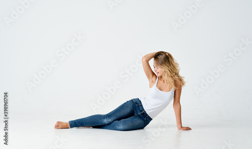 pretty woman sits on the light floor, leaning to the side in full growth  © SHOTPRIME STUDIO