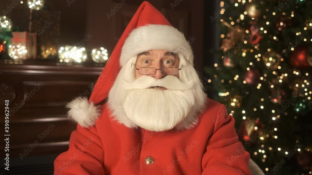 Happy Santa Claus holding gift in hands. Video chat conference. Remote communication happy people. Online greeting Merry Christmas and Happy New Year. Emotion of happiness, holiday atmosphere. Closeup Happy Santa Claus holding gift in hands. Video chat conference. Remote communication happy people. Online greeting Merry Christmas and Happy New Year. Emotion of happiness, holiday atmosphere. Closeup