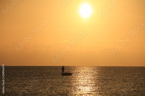 pescadero encima del bote en el atardecer , sol naranja , oceano limpio, vida acuatica, paisaje horizonte © eric.rodriguez