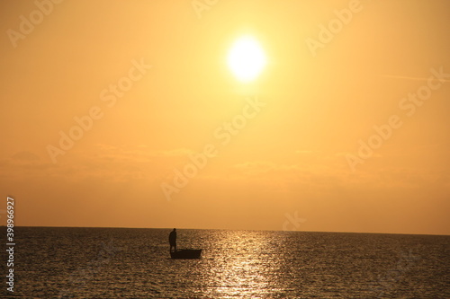 pescadero encima del bote en el atardecer , sol naranja , oceano limpio, vida acuatica, paisaje horizonte © eric.rodriguez