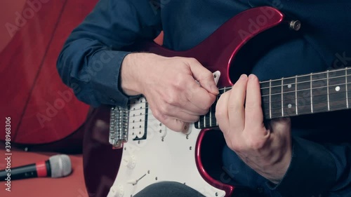 Men hands play electric guitar. Man takes chord then switches pickups to humbucker mode and starts playing heavy metal. Man is wearing a blue shirt photo