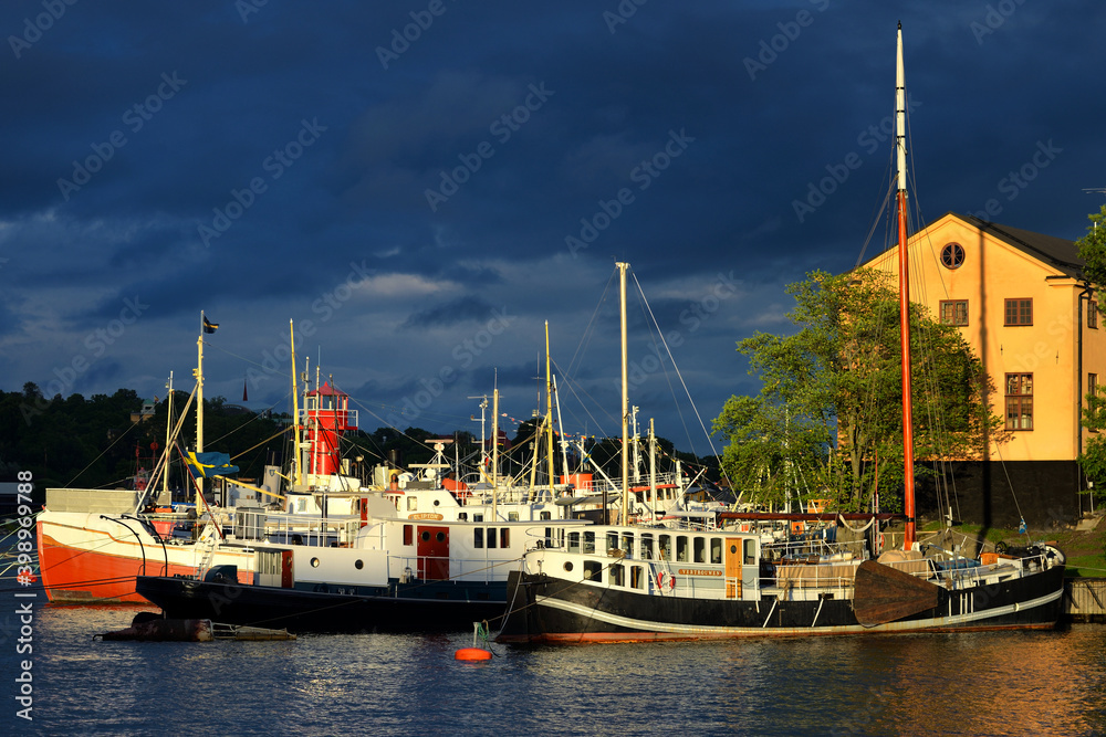Several vessels moored in front of a house against contrast sky after rain