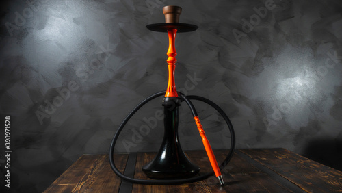 Modern orange hookah on a gray concrete abstract background. Space for text.