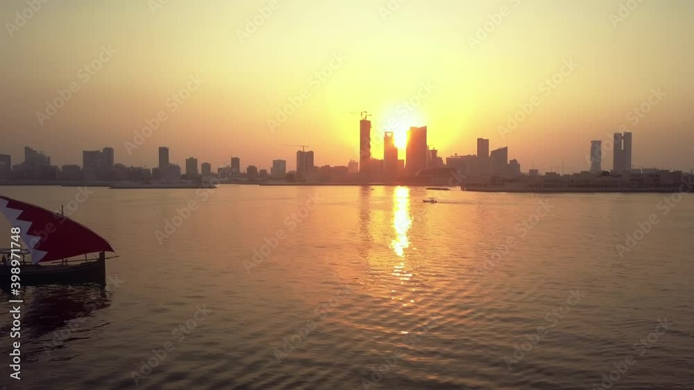 Drone view of the Traditional Arabic Dhow with Bahrain flag branded sails during the sunset time in front of Manama Skyline Drone view of the Traditional Arabic Dhow with Bahrain flag branded sails during the sunset time in front of Manama Skyline
