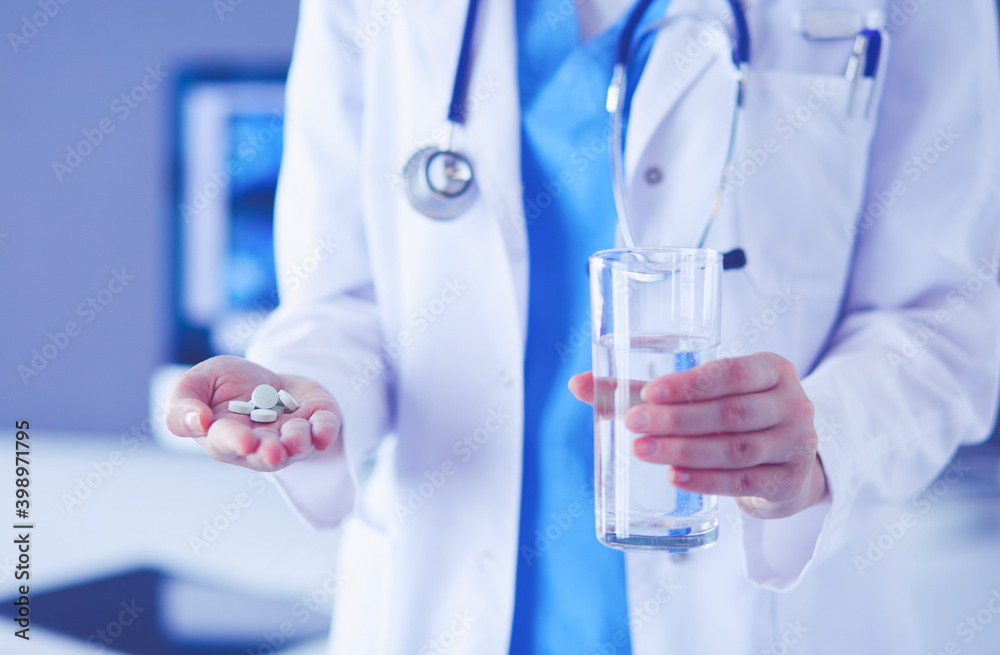 shot of doctor's hands holding pills and glass of water at clinic. shot of doctor's hands holding pills and glass of water at clinic.