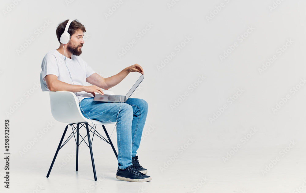 Man sitting on chair in front of laptop in headphones communication technology isolated background