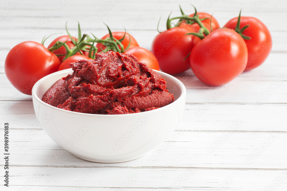 Traditional turkish tomato paste in bowl or spoon with fresh tomatoes on wooden table, homemade healthy food Traditional turkish tomato paste in bowl or spoon with fresh tomatoes on wooden table, homemade healthy food