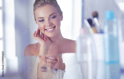 Free Download Young woman in bathrobe looking in bathroom mirror - GFXLoad