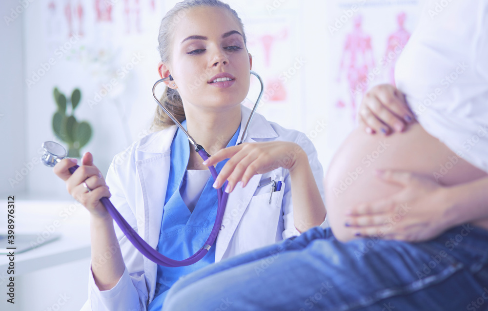 Young woman doctor with stethoscope speaking with pregnant woman at hospital. Young woman doctor with stethoscope speaking with pregnant woman at hospital.