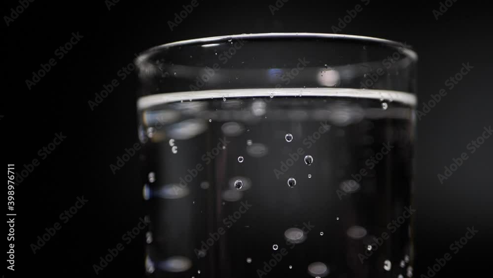 Mineral water is poured into a glass. The glass rotates slowly. The sparkling water in the glass bubbles in a slow motion, refreshing the carbonated drink. Mineral water is poured into a glass. The glass rotates slowly. The sparkling water in the glass bubbles in a slow motion, refreshing the carbonated drink.