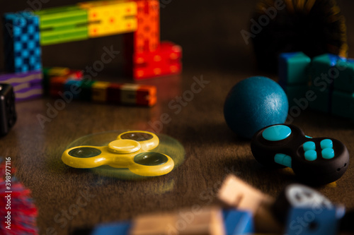 Spinning yellow fidget spinner surrounded by other fidget toys for children. 