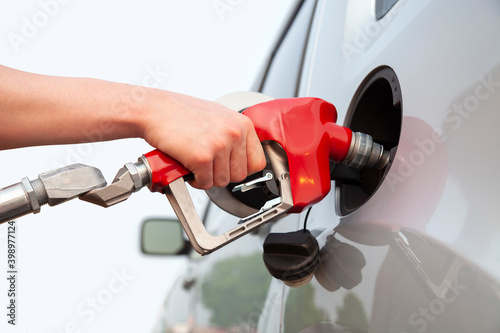 Isolated arm and hand of a young man pumping gas into a car