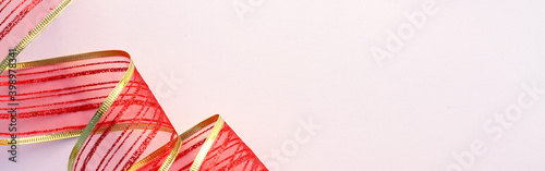 Christmas and New Year decoration, twisted red and gold decorative ribbon isolated on white background, horizontal panoramic photo 