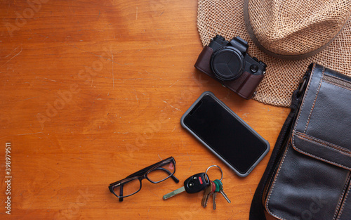 digital compact camera on orange vintage wood table top view copy space, included black screen cellphone display eyeglasses hat keys bag strolling