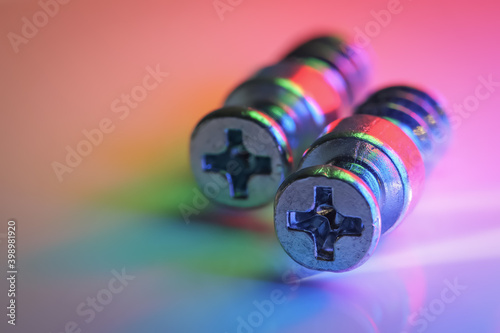 Two wood screws with colorful lighting effects used purple magenta green and red macro lights
