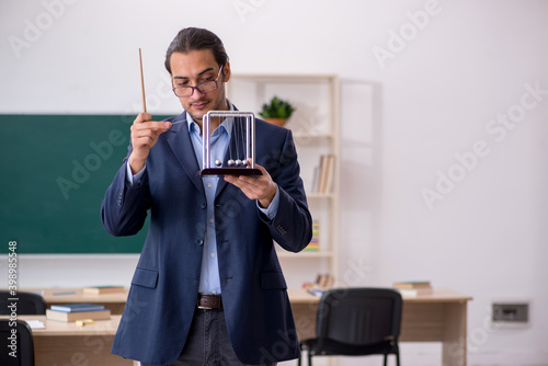 Young male teacher physicist in front of green board